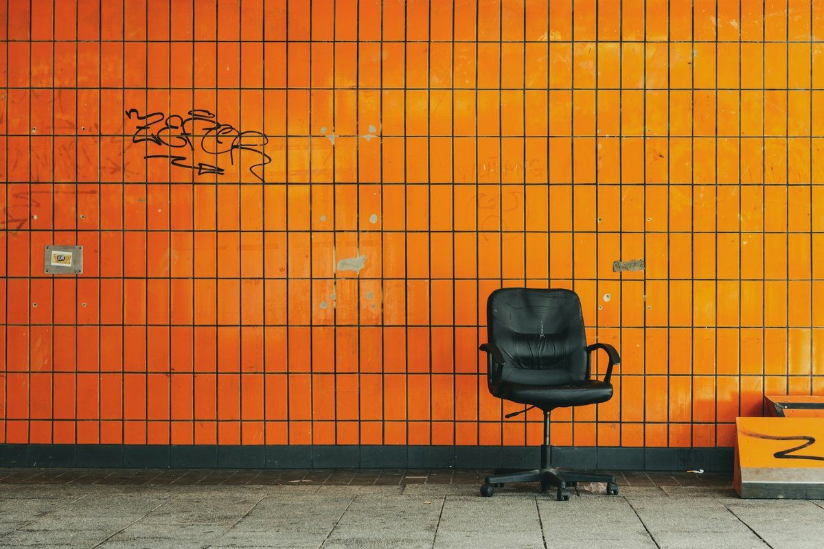 Chaise de bureau noire à roulettes devant un mur carrelé orange