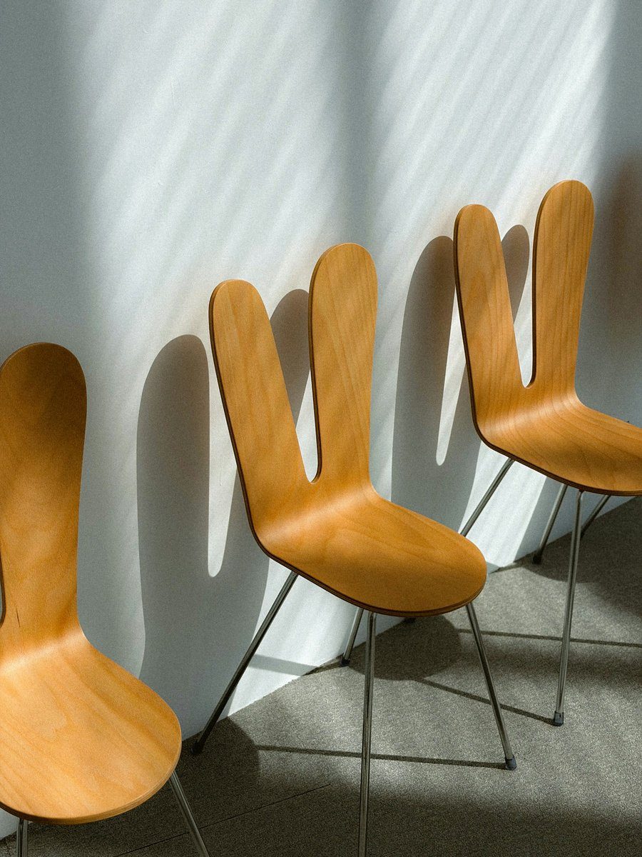 Chaises en bois courbé alignées contre un mur, entre soleil et ombre