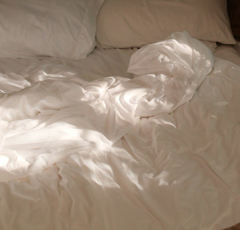 Lit aux draps blancs froissés baigné dans une lumière douce