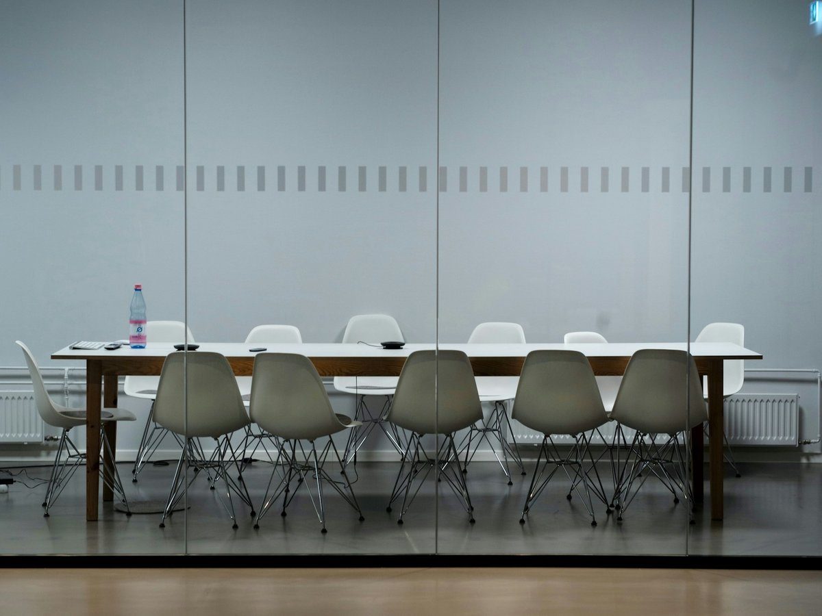Salle de réunion vide avec des chaises blanches alignées autour d'une longue table