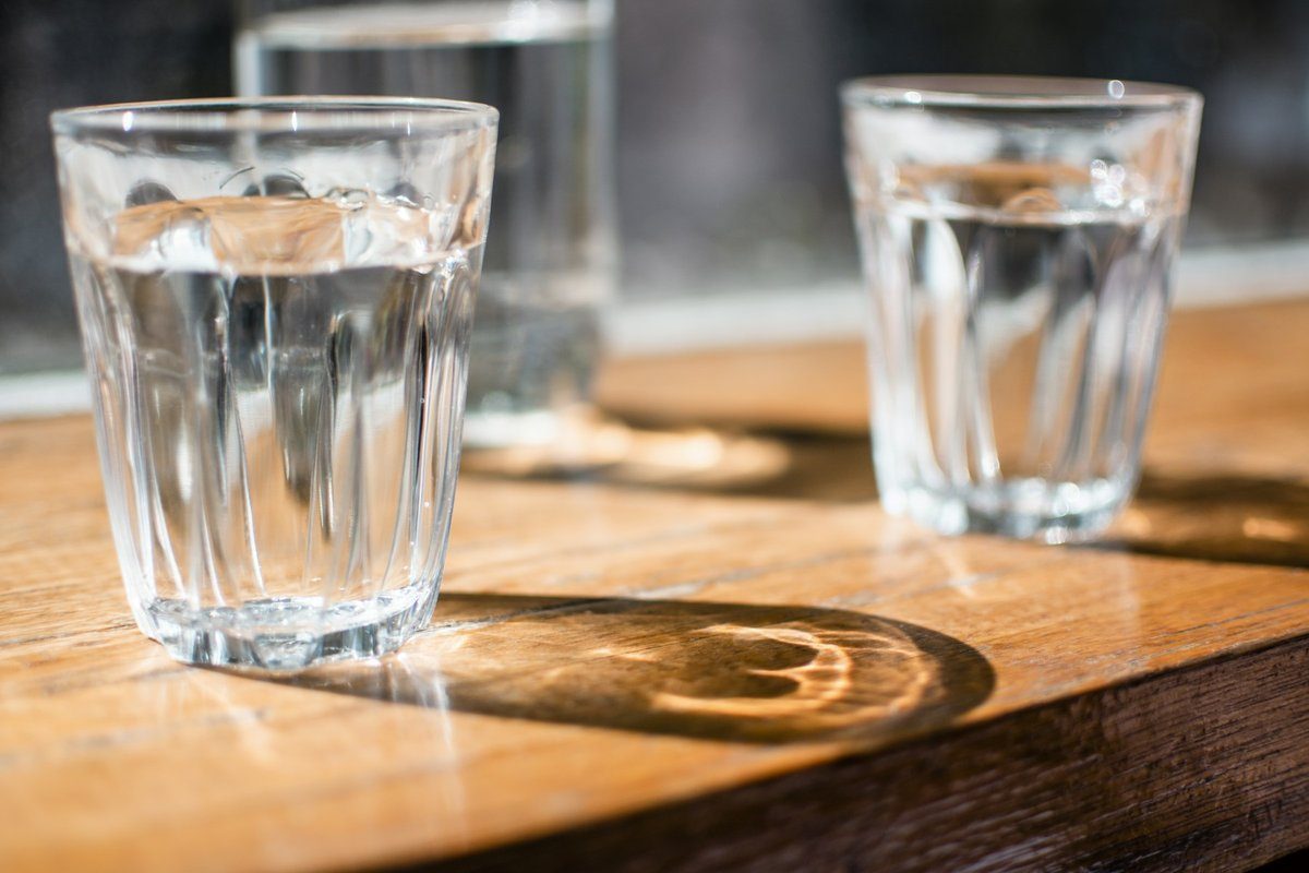 Deux verres d'eau au soleil sur une table en bois